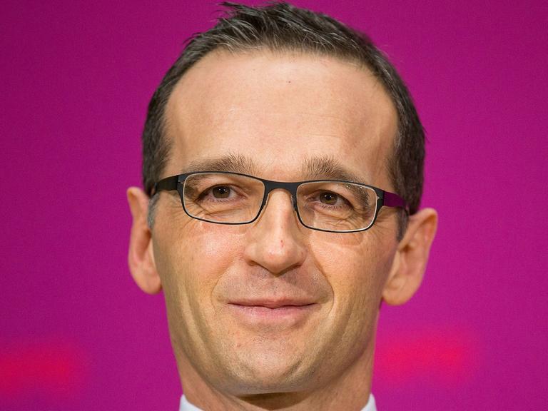 Vor pinkfarbenem Hintergrund schaut Justizminister Heiko Maas in die Kamera