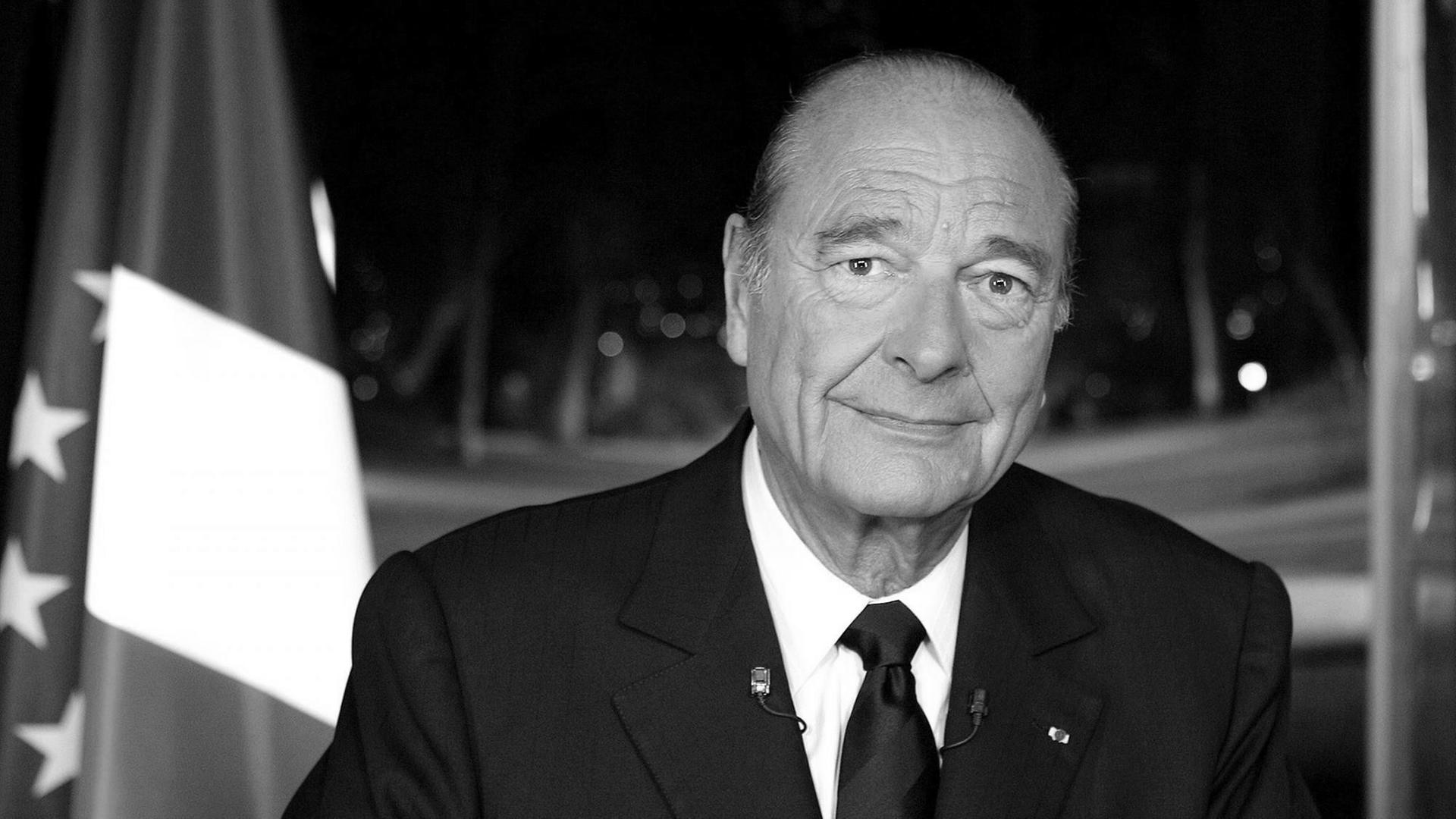 Jacques Chirac neben einer Flagge von Frankreich