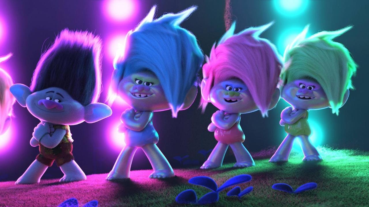 Filmszene aus "Trolls World Tour": Auf einer Bühne stehen Troll-Animationsfigürchen in vor violetten und grünen Scheinwerfern.