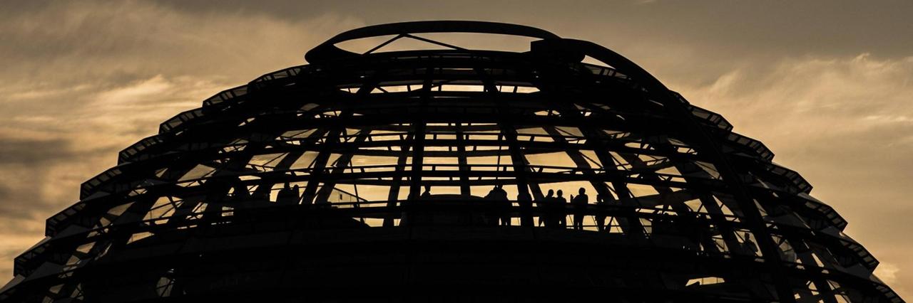 Besucher stehen in der Kuppel des Reichstags, aufgenommen während des Sonnenuntergangs.