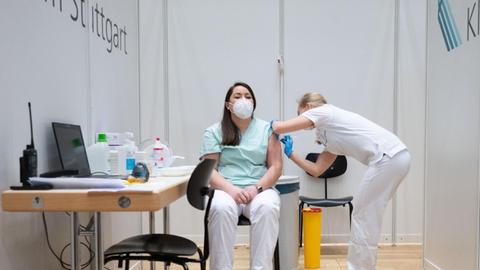 Christine Helbig (l), Pflegekraft am Klinikum Stuttgart wird im Impfzentrum des Klinikum Stuttgart von einer Ärztin mit einer Dosis eines Covid-19 Impfstoffes geimpft. Helbig hatte am vormittag Dienst in einer Covid-19 Station des Klinikum Stuttgart und kam direkt von der Arbeit zur Impfung. Sie ist eine der ersten Menschen in Baden-Württemberg, die geimpft wurden. Am Sonntag haben die Corona-Impfungen mit dem Impfstoff von Biontech/Pfizer in Deutschland begonnen.