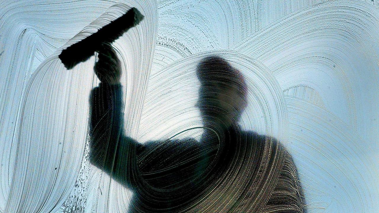 Kunstvolle Streifen auf dem Glas zaubert ein Fensterputzer während seiner Arbeit.Können Helfer-Jobs und Zeitarbeit Flüchtlingen einen Einstieg in den Arbeitsmarkt ermöglichen? Oder sind sie bei der Integration eine Sackgasse?