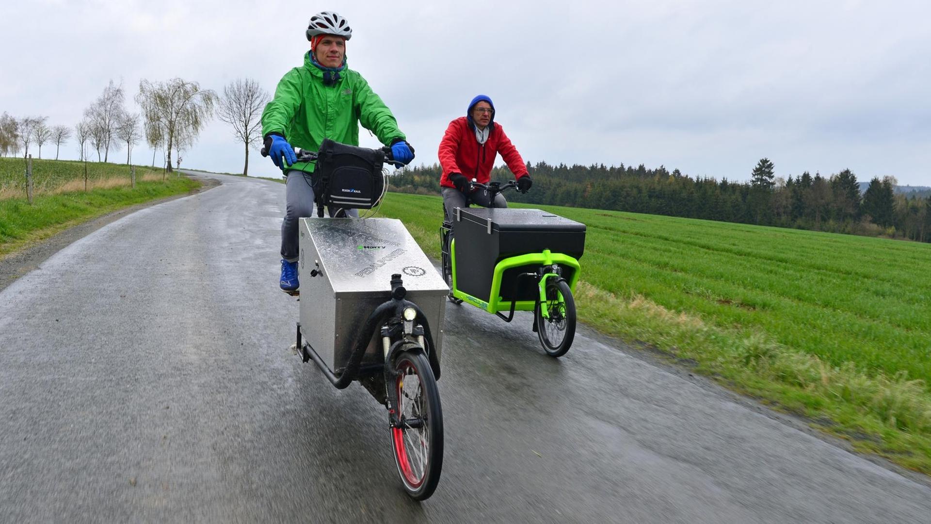 Bei einem Test von E-Lastenfahrrädern fahren Tester auf zwei speziellen E-Bikes.