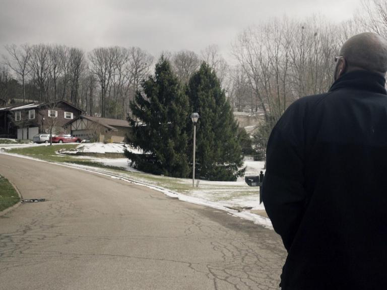 Ein Mann läuft eine Straße in einer amerikanischen Wohnsiedlung entlang. Zu sehen ist er nur von hinten.