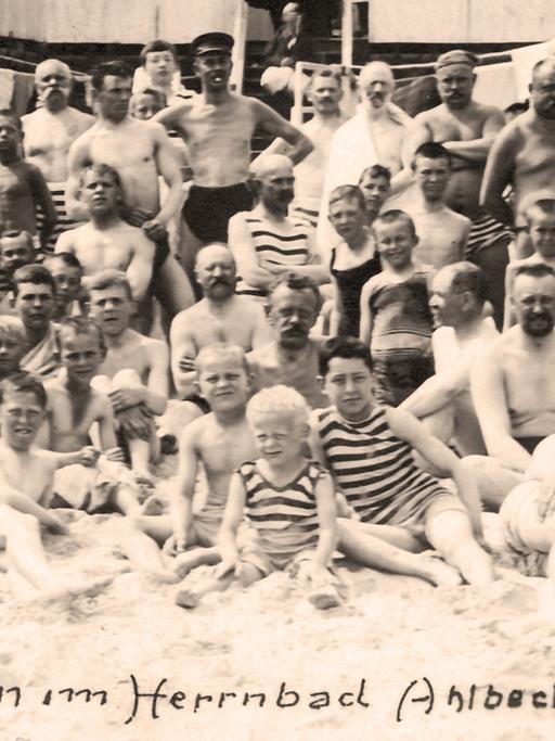 Die historische Fotografie mit dem Schriftzug "Mänliche Schönheiten im Herrenbad Ahlbeck 1912" aus dem Jahr 1912 zeigt Männer und Kinder im Herrenbad von Ahlbeck, Ostseebad, auf der Insel Usedom.