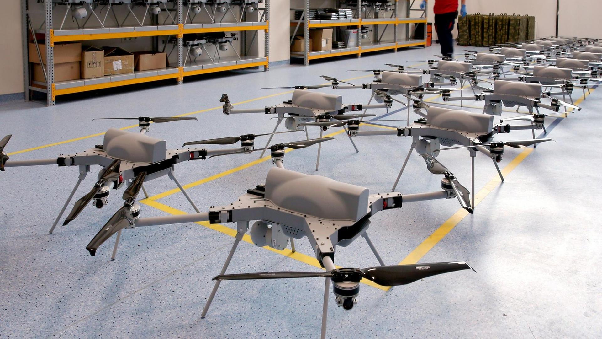 Aufgereihte Drohnen des Typs Kargu stehen nebeneinander auf einem blauen Linoliumboden in einer Lagerhalle des türkischen Herstellers STM