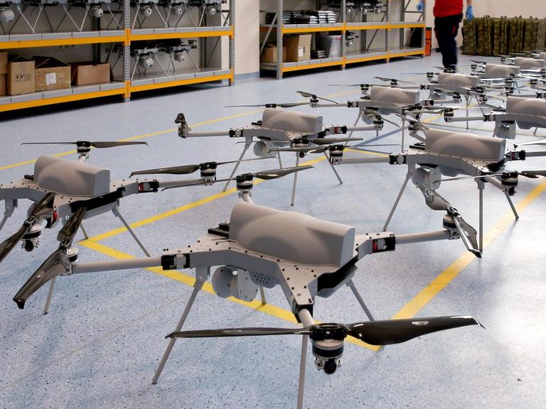 Aufgereihte Drohnen des Typs Kargu stehen nebeneinander auf einem blauen Linoliumboden in einer Lagerhalle des türkischen Herstellers STM
