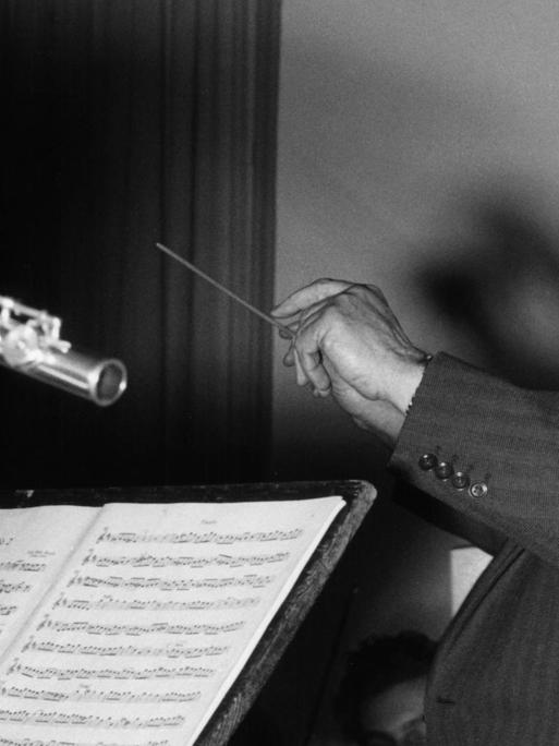 Der deutsche Komponist und Dirigent Paul Hindemith bei einer Orchesterprobe, bei der er mit einem Flötisten in Blickkontakt steht.