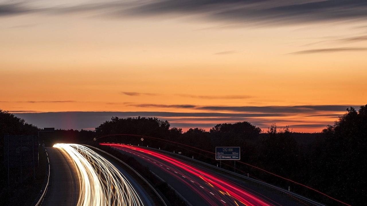 Die Sonne geht am Abend, den 03.10.2012 über der Bundesautobahn (BAB) A15 in der Nähe von Cottbus, Brandenburg in Deutschland unter. Die unzähligen Autos verschwimmen und erzeugen roten und gelben Lichtspuren.