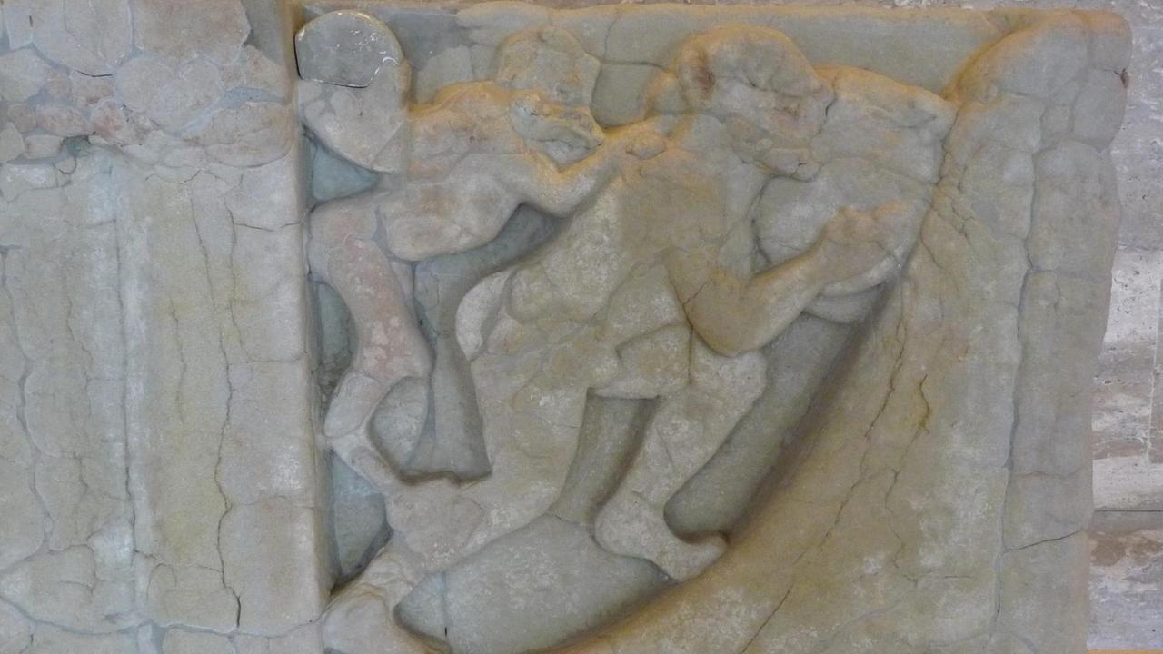 Mit einem geflügelten Dämon auf seiner Schulter rollt Sisyphus, König von Korinth, einen grossen Stein den Berg hinauf - auf Sandstein

