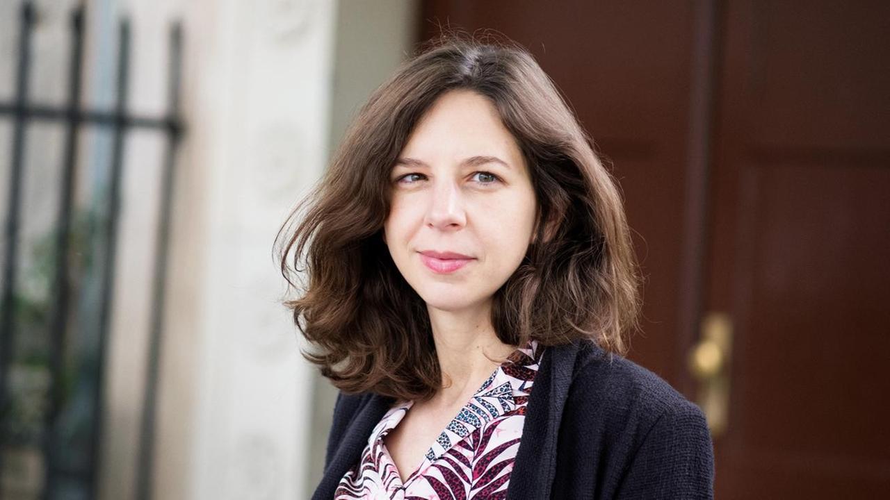 Lina Muzur steht vor einer braunen Tür und schaut in die Kamera.