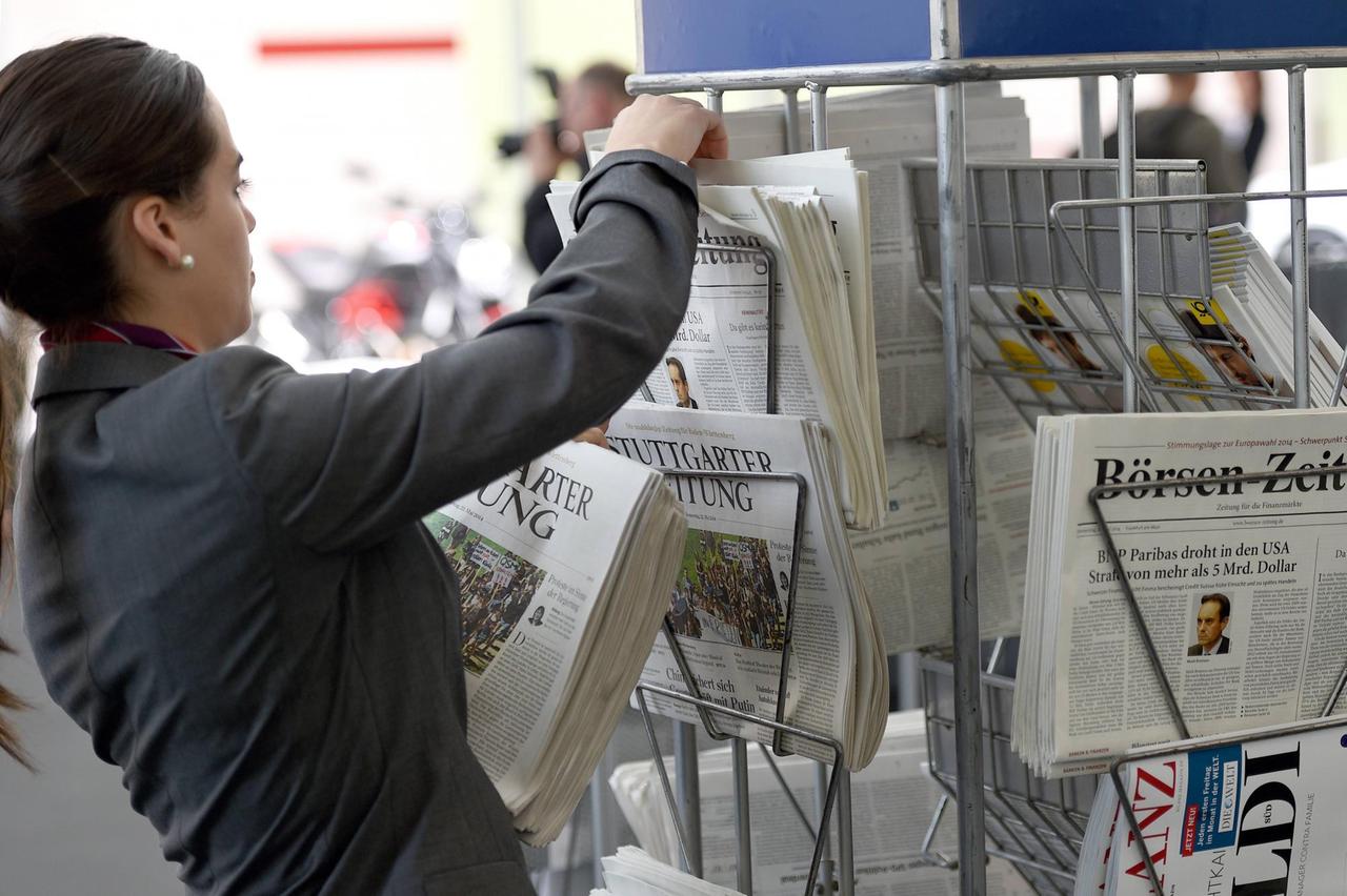 Eine Frau füllt einen Zeitungsständer auf.