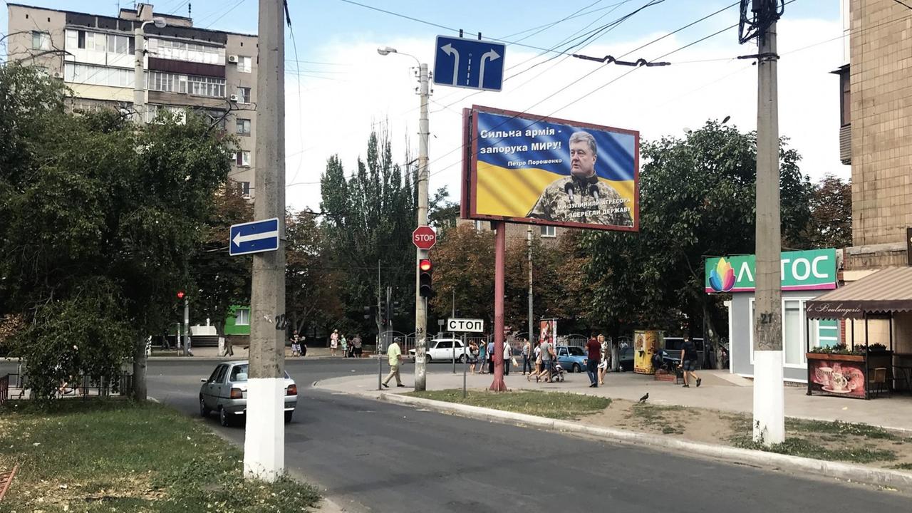 Straßenecke in Mariupol und auf dem Plakat ein Zitat von Präsident Poroschenko: "Eine starke Armee ist der Garant für Frieden"