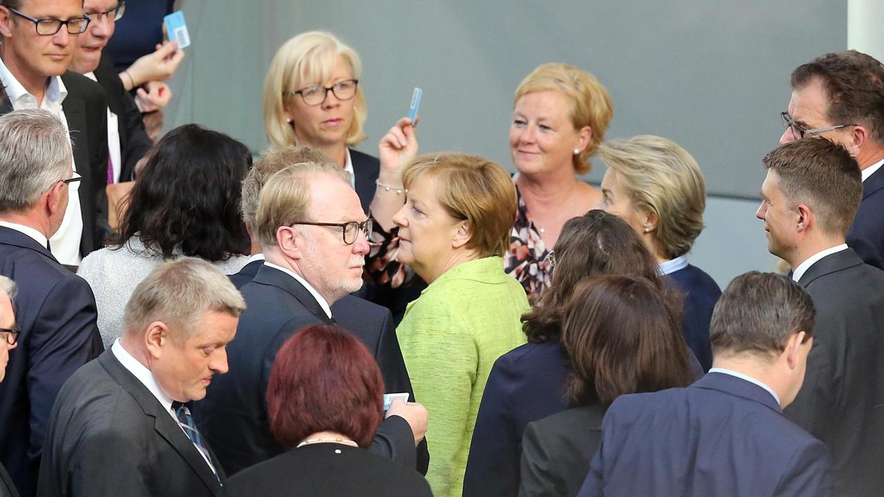 Merkel und andere viele andere Abgeordnete auf dem Weg zur Urne.