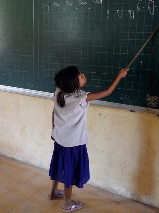 Eine Schülerin steht am 11.10.2013 in Phnom Penh (Kambodscha) in der Kdei Chas Primary School an der Tafel und zeigt mit einem Zeigestock auf Buchstaben in Khmer-Schrift.