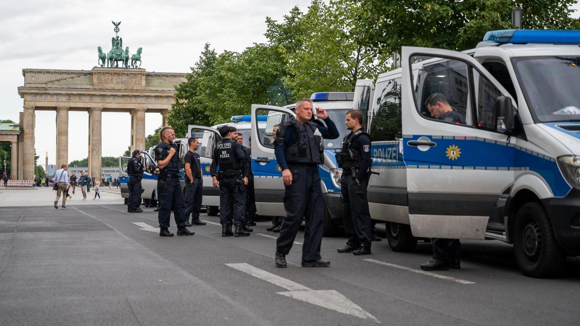 29.08.2020, Berlin: Polizisten stehen am frühen Morgen neben Polizeifahrzeugen vor dem Brandenburger Tor.