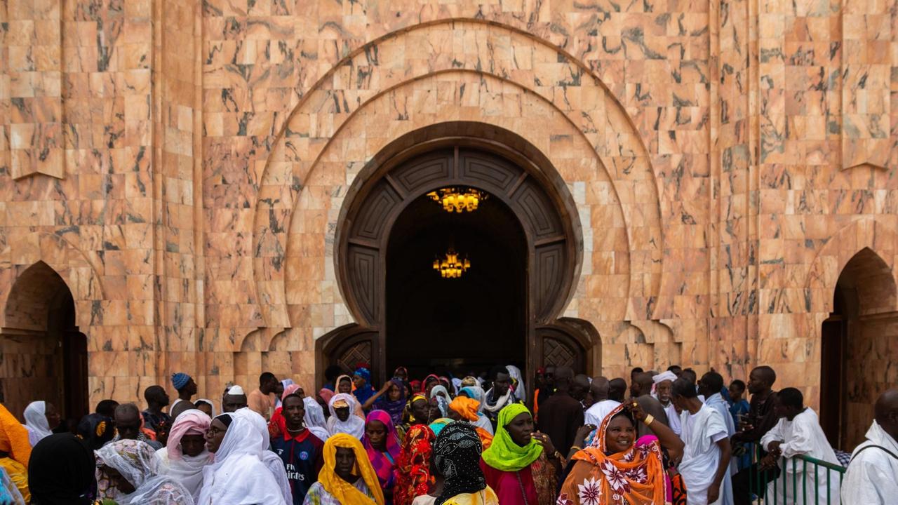 Viele Gläubige drängen durch das Tor der großen Moschee von Touba.