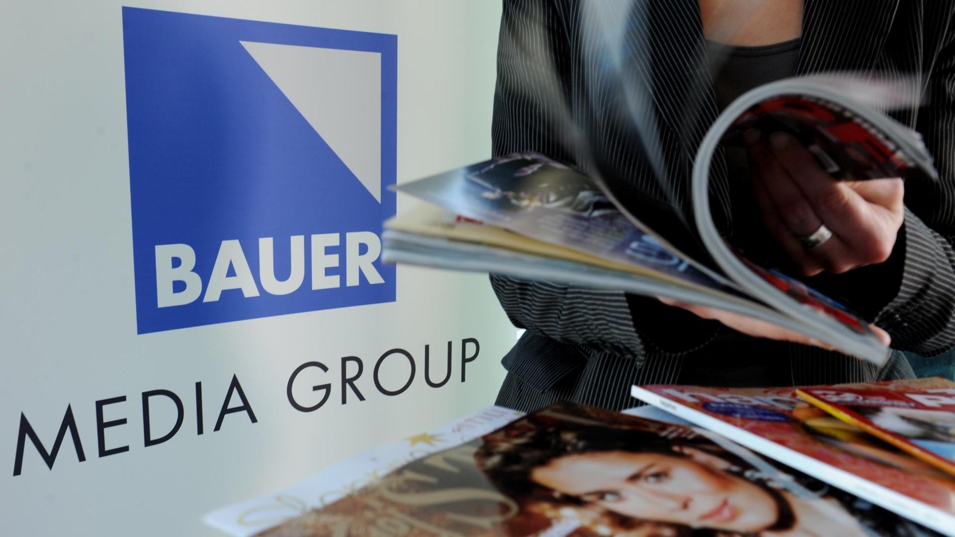 Eine Frau blättert auf der Jahrespressekonferenz der Bauer Media Group in Hamburg vor dem Firmenlogo in einer Zeitschrift.