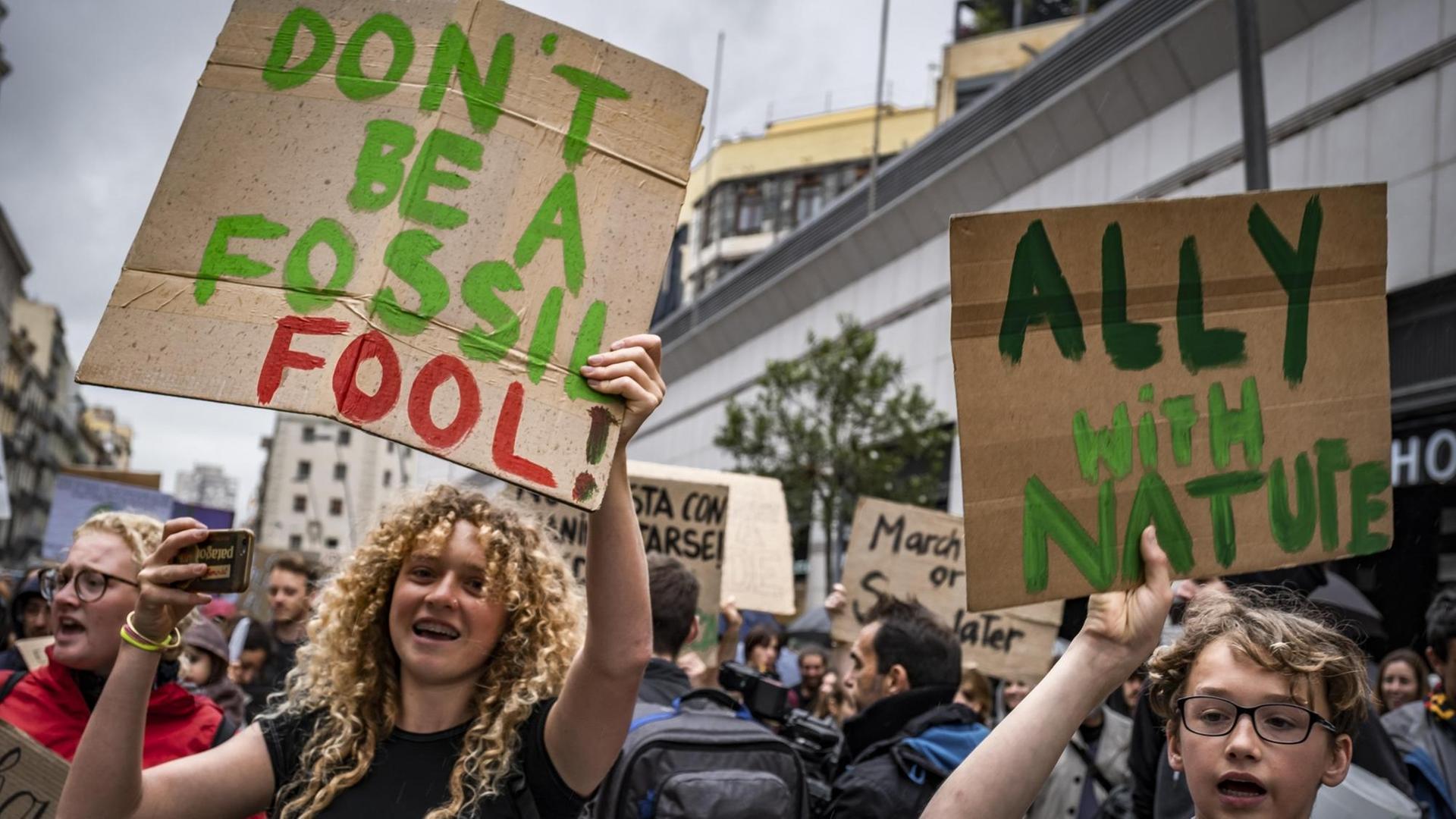 Jugendliche DemonstrantInnen die ein Schild mit der Aufschrift "Don't be a fossil - Fool!" hochhalten.