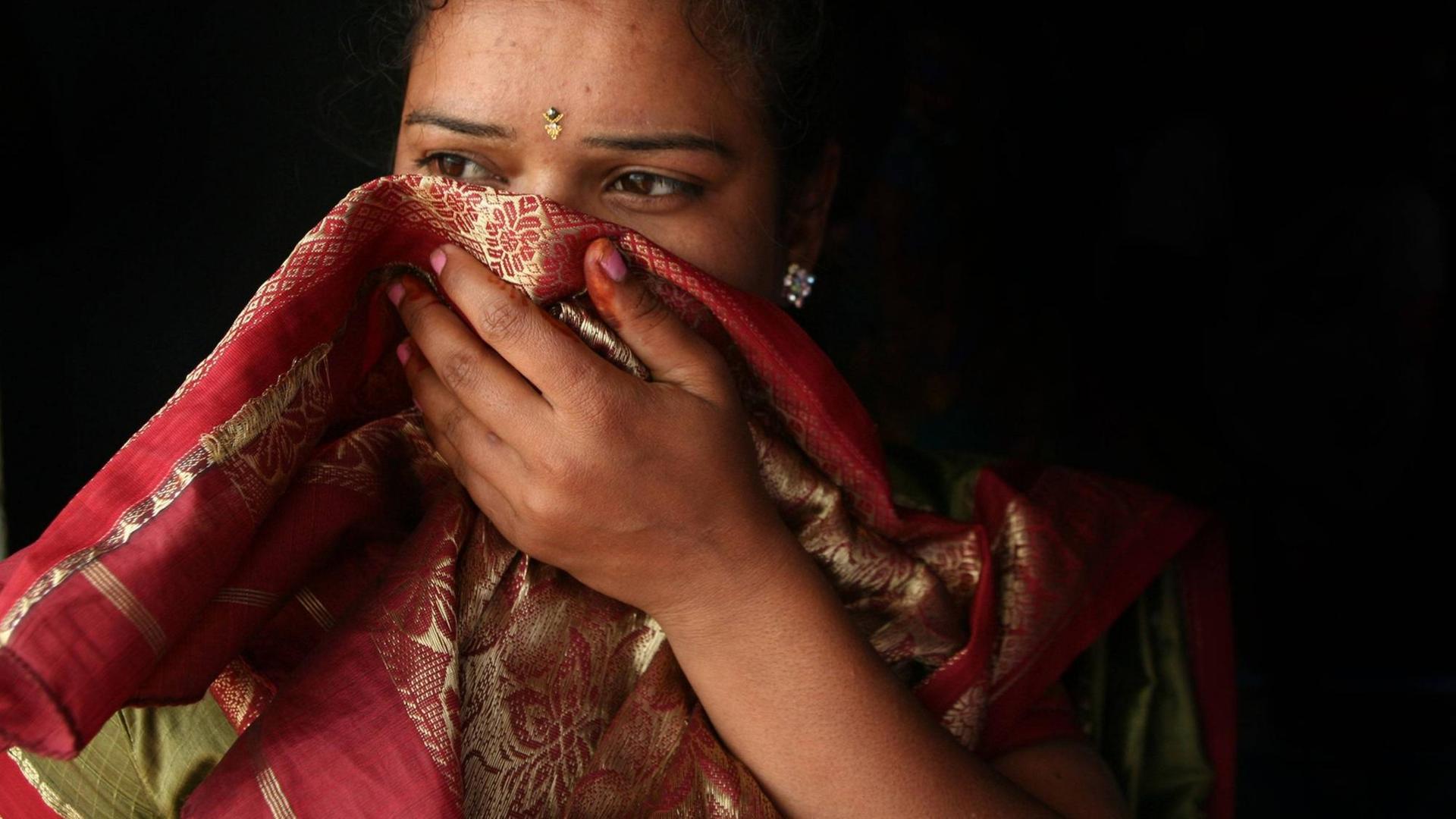 Portrait einer indischen Frau deren Gesicht teilweise von einem Tuch bedeckt ist