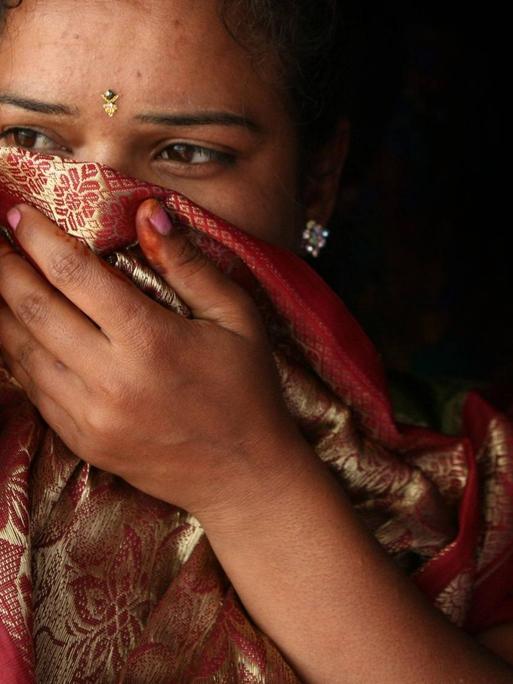 Portrait einer indischen Frau deren Gesicht teilweise von einem Tuch bedeckt ist