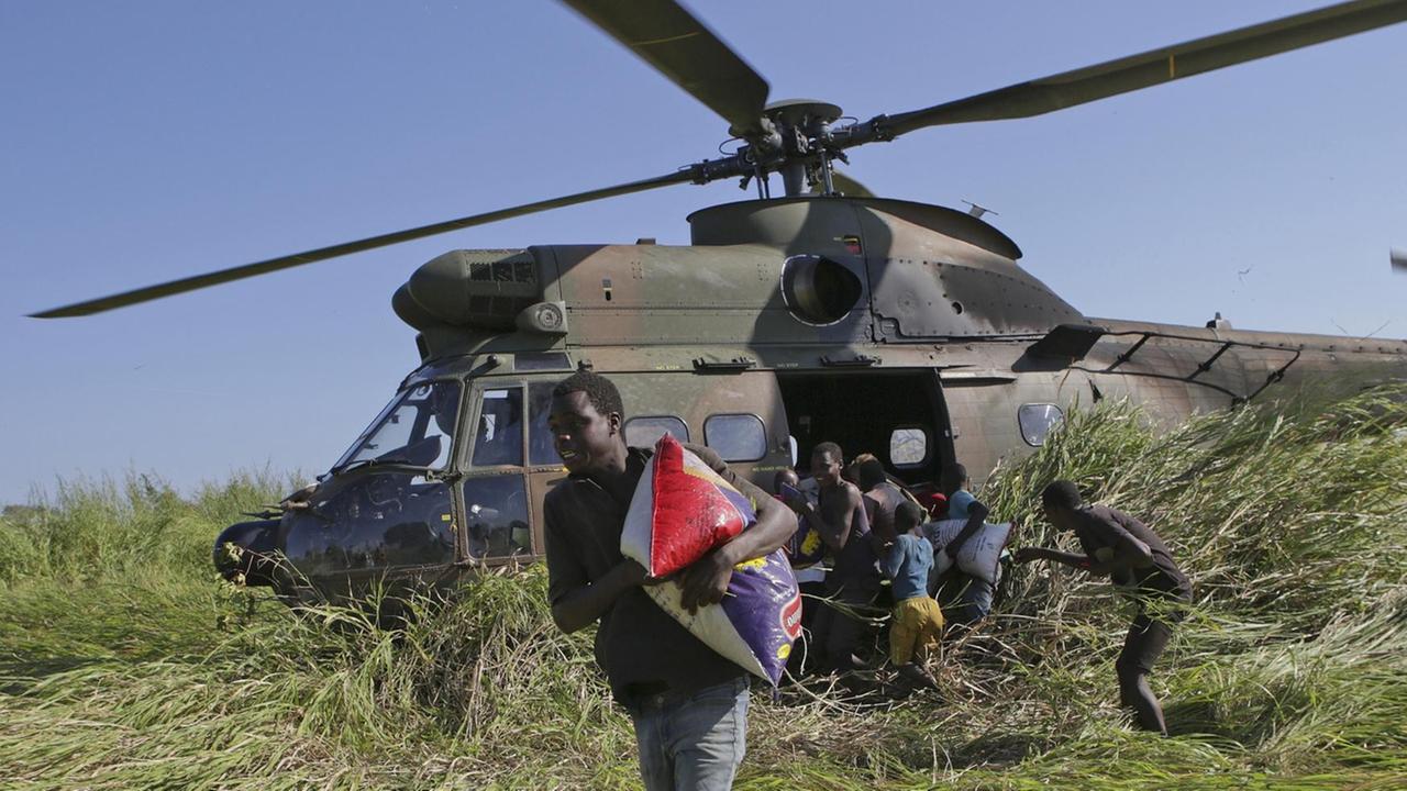 Im März 2019 warten Einwohner von Gwaragwara in Mosambik auf Reis, der aus einem Hubschrauber der South African Airforce verteilt wird - die Region wurde vom Zyklon Idai verwüstet.