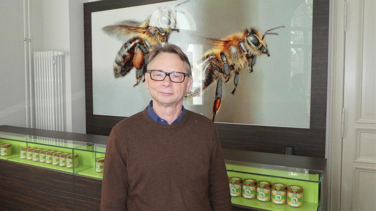 Mann steht vor zwei großen, gemalten Bienen