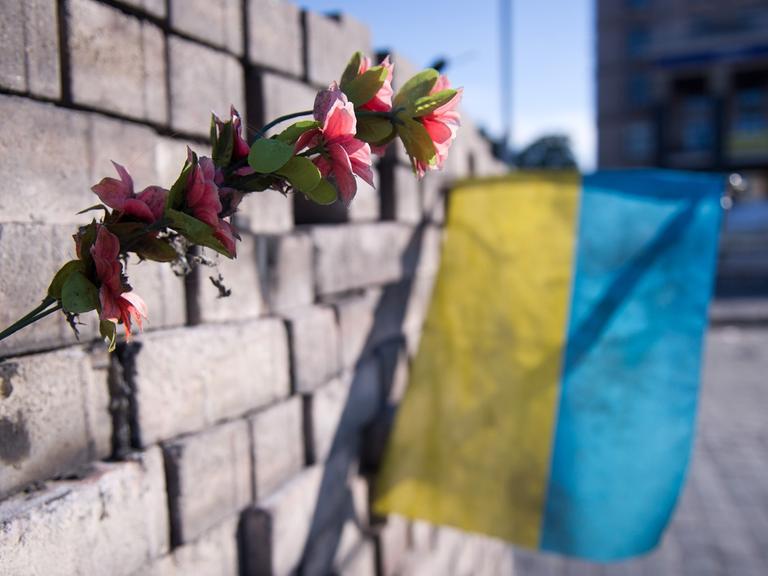 Kiew, Ukraine: Eine Blume und eine ukrainische Flagge auf dem Maidan in einer Barrikade