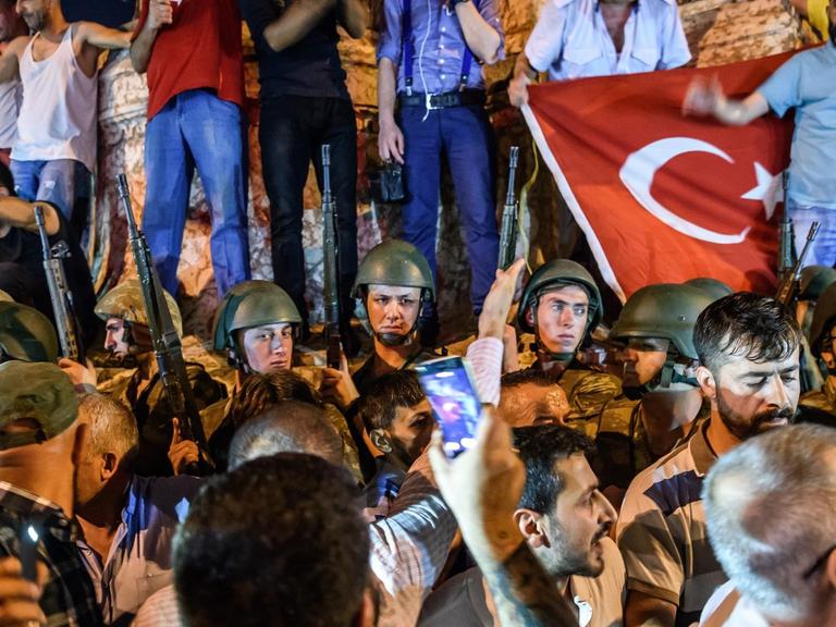 Türkische Soldaten stehen in Istanbul zwischen Menschen, die gegen den Militärputsch demonstrieren.