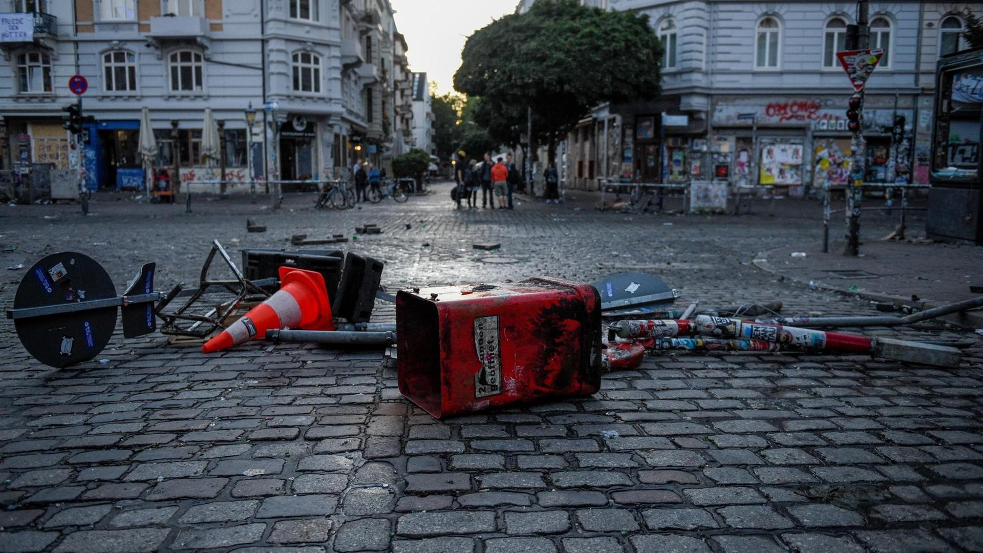 Zerstörte Straßenschilder und Mülleimer liegen auf der Straße.