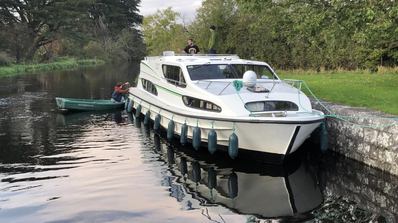 Ein Hausboot liegt vertäut auf einem Fluss