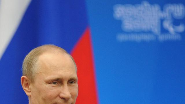 Ein Bild von Wladimir Putin vor einer russischen Flagge im Hintergrund