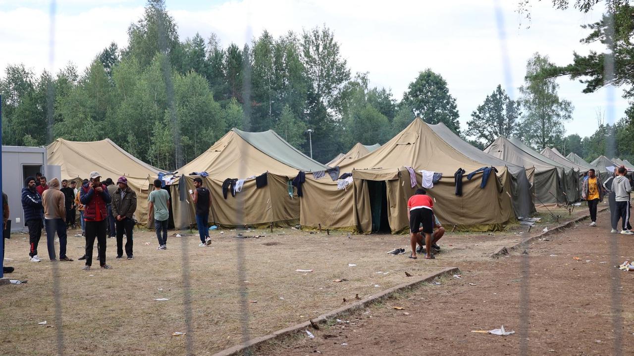 Hinter einem Zaun stehen mehrere Zelte in einem Aufnahmelager.