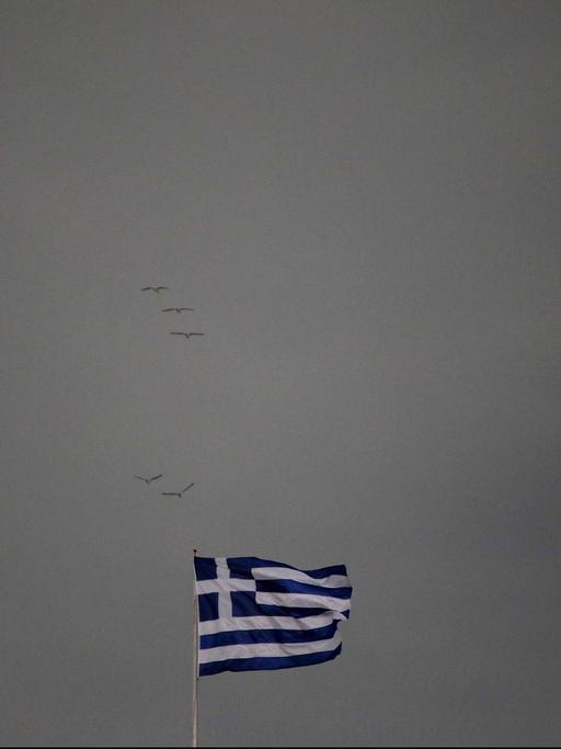 Eine griechische Flagge weht vor dunklem Hintergrund.