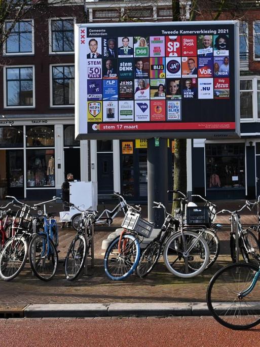 Ein Radfahrer fährt in Amsterdam an einem Ständer mit den Plakaten aller an den niederländischen Parlamentswahlen teilnehmenden Parteien vorbei.