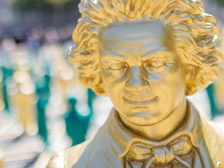 Nahaufnahme eines goldenen, lächelnden Beethoven-Gesichtes, das während der Installation im Mai 2019 in Bonn entstand, bei der 700 lächelnde Figuren den zentralen Platz in Bonn füllten.