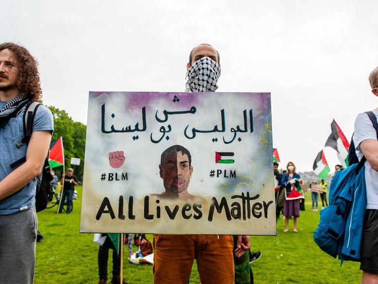 Ein Demonstrant hält ein Schild mit der Aufschrift: "#BLM #PLM All Lives Matter". Ein Demonstrant hält ein Schild mit der Aufschrift: "#BLM #PLM All Lives Matter".
