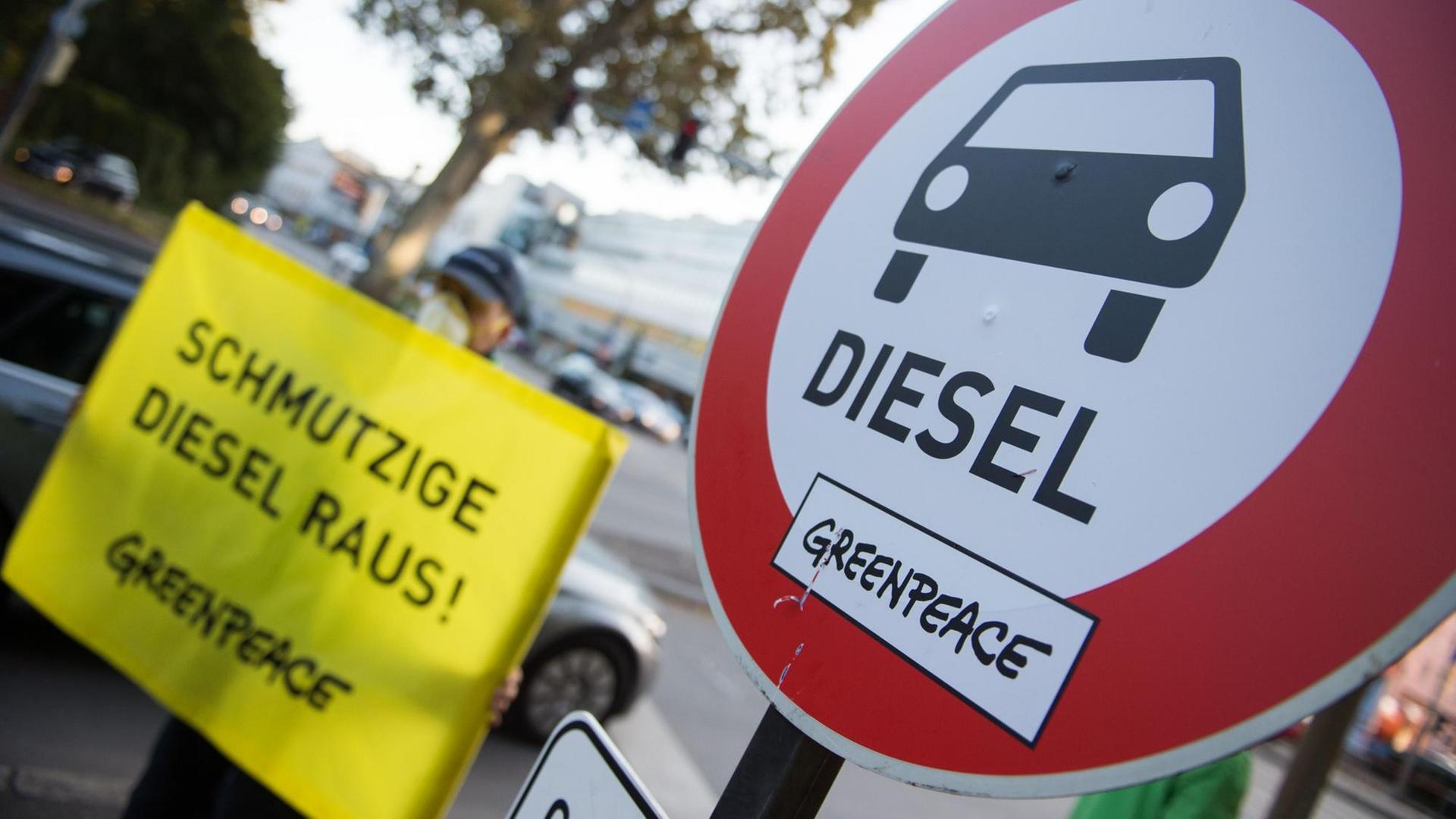 Schild mit der Aufschrift "Schmutzige Diesel raus!" neben einem "Verbotsschild für Dieselfahrzeuge", das von Greenpeace für die Aktion aufgestellt wurde.