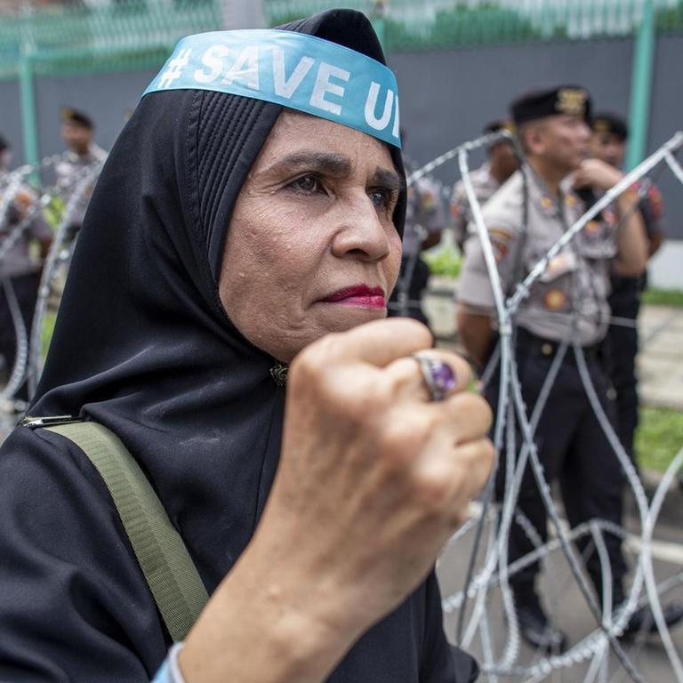 Tausenden Muslime protestieren vor der chinesischen Botschaft in Jakarta, Indonesien. Hier eine Frau mit erhobener Faust vor Stacheldraht, 27.12.2019.