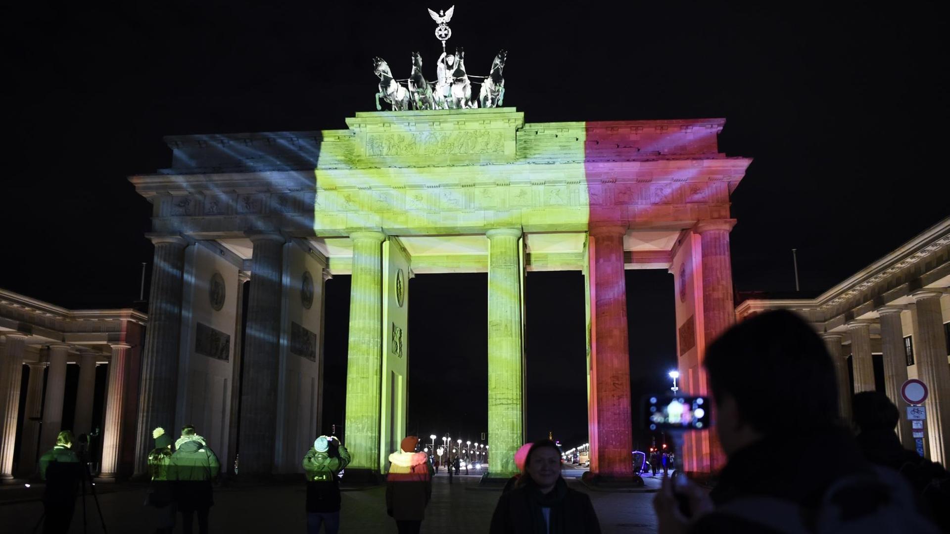Menschen machen Fotos von dem in den Farben der belgischen Flagge angestrahlten Brandenburger Tor am Abend nach den morgendlichen Anschlägen in Brüssel am 22.03.2016.