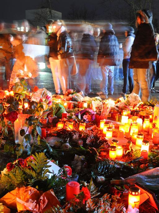 Das Bild zeigt Blumen, Grablichter und trauernde Menschen einen Tag nach dem Amoklauf von Winnenden.