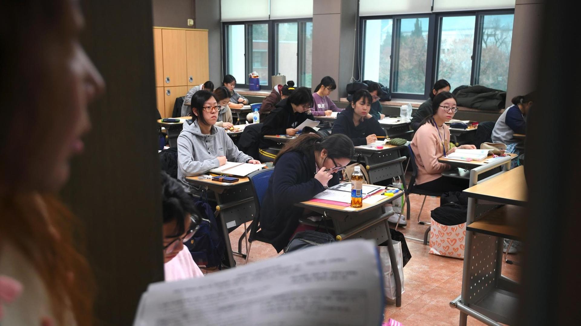 An exam inspector (L) enters an exam room for the annual College Scholastic Ability Test, a standardised exam for college entrance, at a high school in Seoul on November 23, 2017. An annual hush descended upon South Korea on November 23 as hundreds of thousands of students sat the crucial collegue entrance exam, delayed for a week by a rare quake. / AFP PHOTO / JUNG Yeon-Je