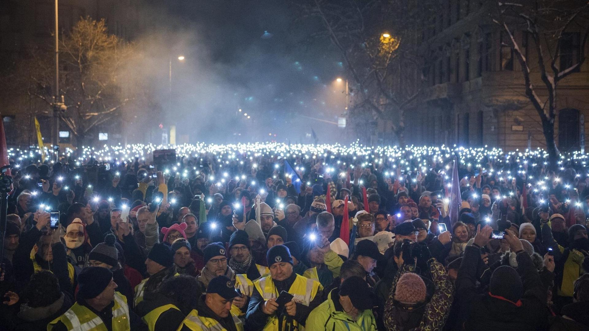 Das Foto zeigt Proteste gegen die ungarische Regierung, bei denen die Demonstraten die Lampen ihrer Handys einschalten.