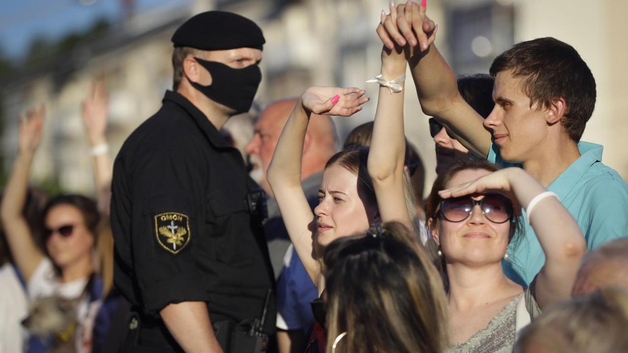 Ein Polizeibeamter steht in Minsk vor Demonstranaten. Nur er trägt eine Maske.