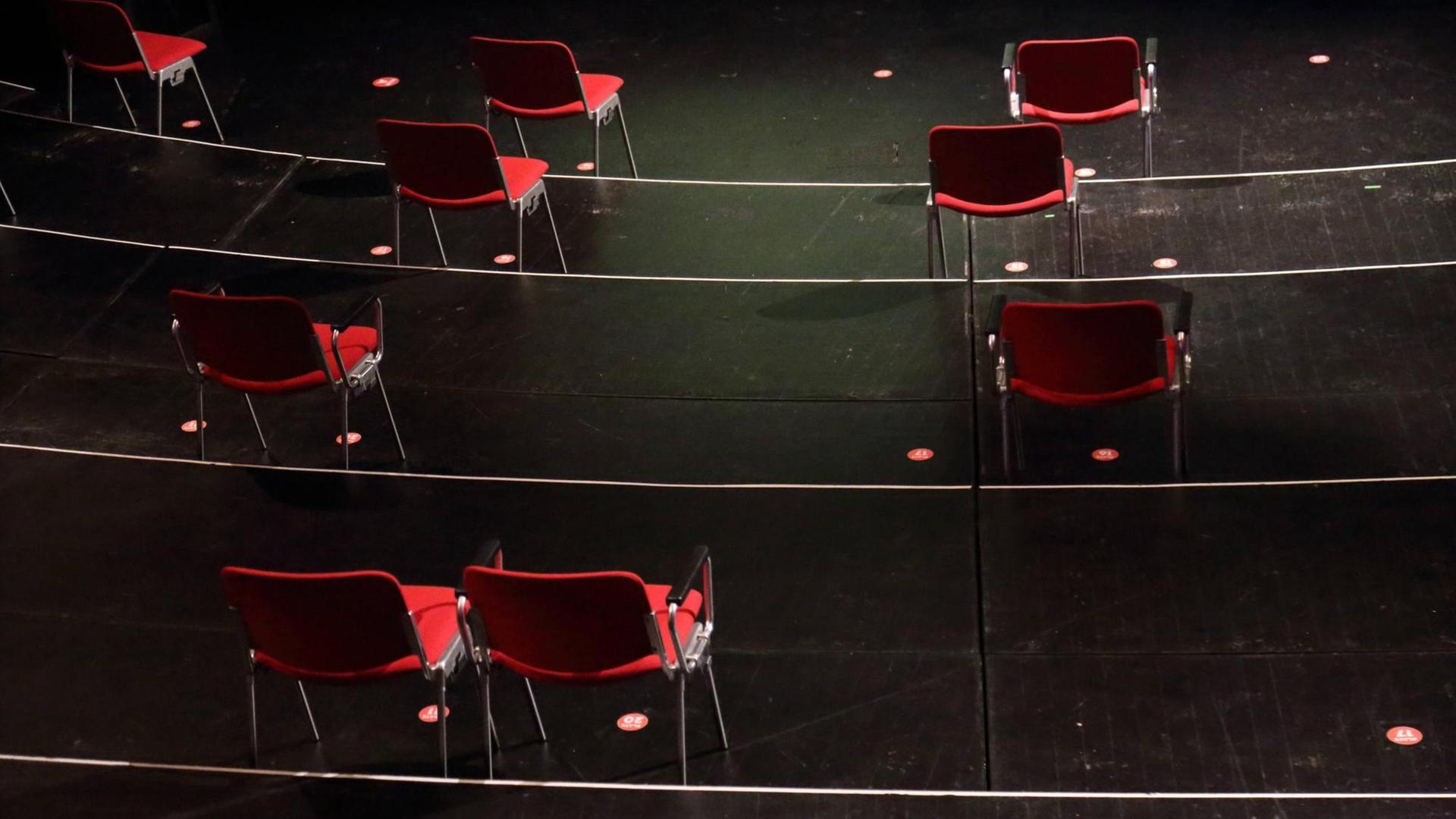 In einem menschenleeren Theatersaal stehen vereinzelt einige rote Stühle.