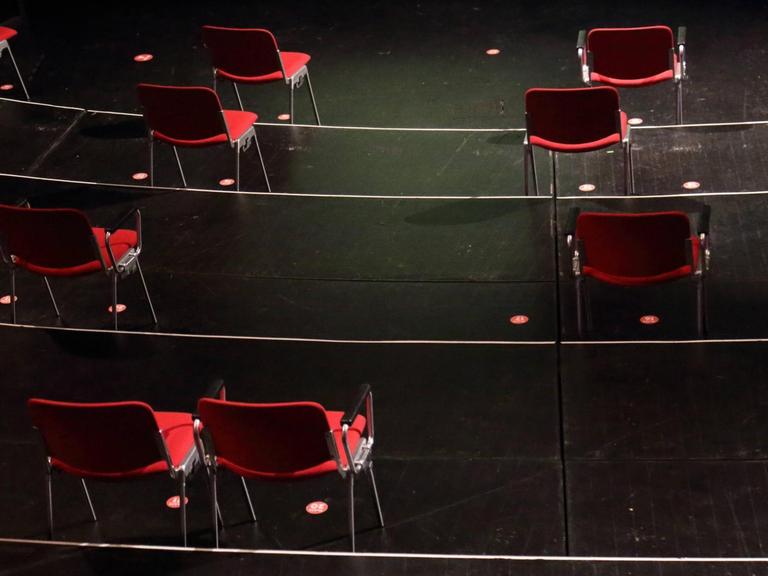 In einem menschenleeren Theatersaal stehen vereinzelt einige rote Stühle.