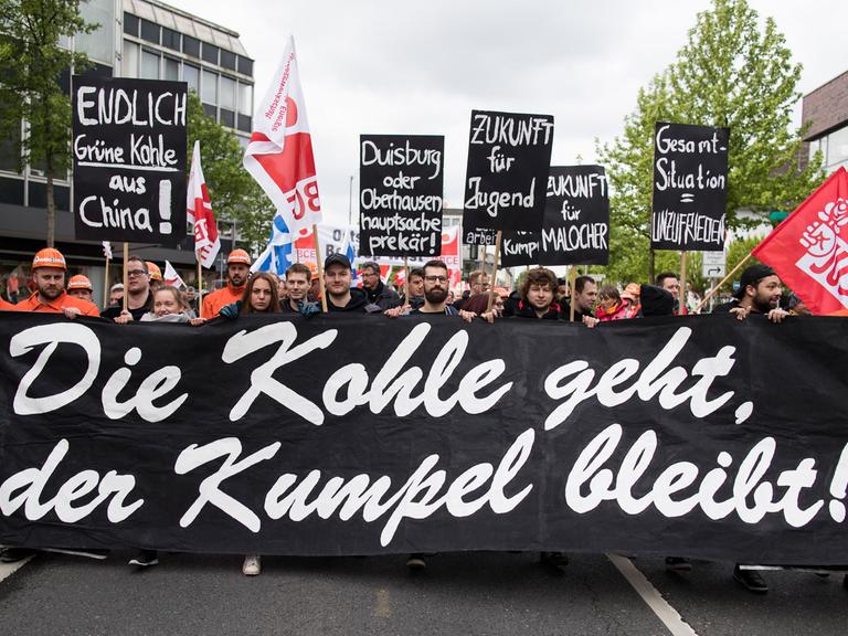 "Die Kohle geht, der Kumpel bleibt" steht mit weißer Schrift auf einem schwarzen Banner während eines Demonstrationszuges in Bottrop am 1. Mai 2018