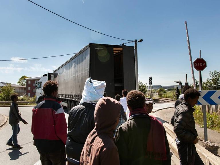 Flüchtlinge und ein Laster auf einer Straße in Calais