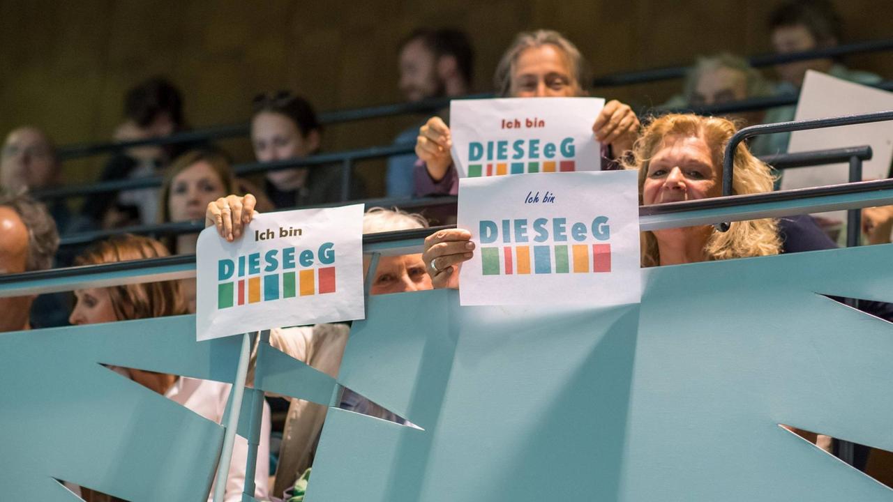 Besucher der Bezirksverordnetenversammlung protestieren mit Schildern mit der Aufschrift "Ich bin DIESE e.g.".
