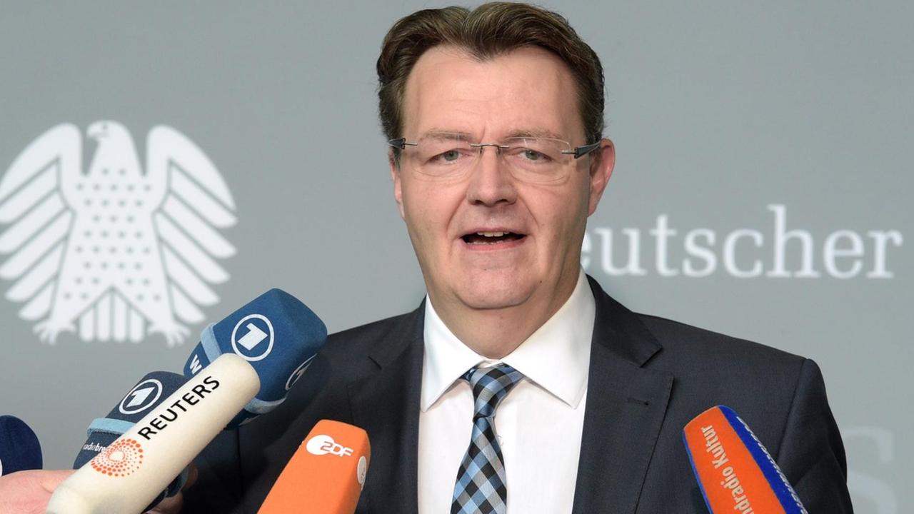 Frieser steht vor einer grauen Wand mit der Aufschrift "Deutscher Bundestag" mit dem Bundesadler. Er spricht in die Mikrofone mehrerer Fernsehsender.